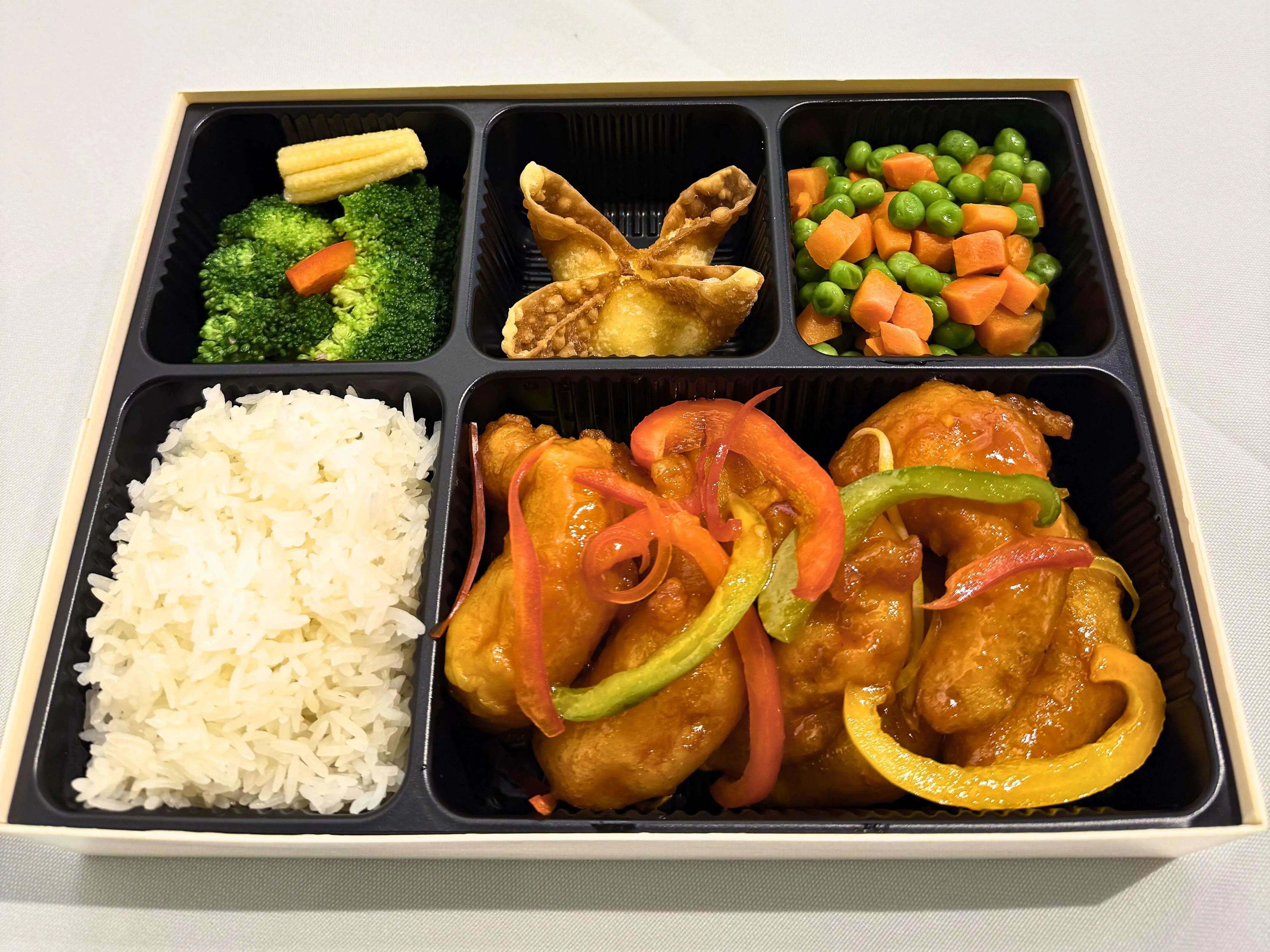 Bento box with sweet and sour chicken, rice, veggies, and a fried pastry at Big 8, a Chinese Restaurant in Lincoln